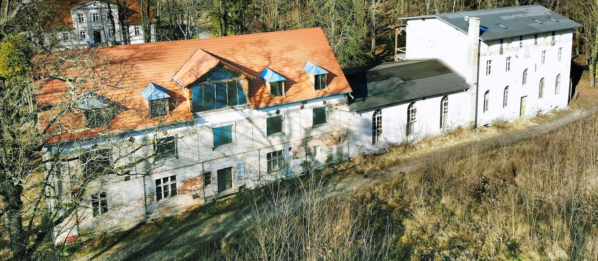 Widok z lotu ptaka na zabytkowy pałac uzdrowiskowy w Obornikach Śląskich z czerwonym dachem i lukarnami